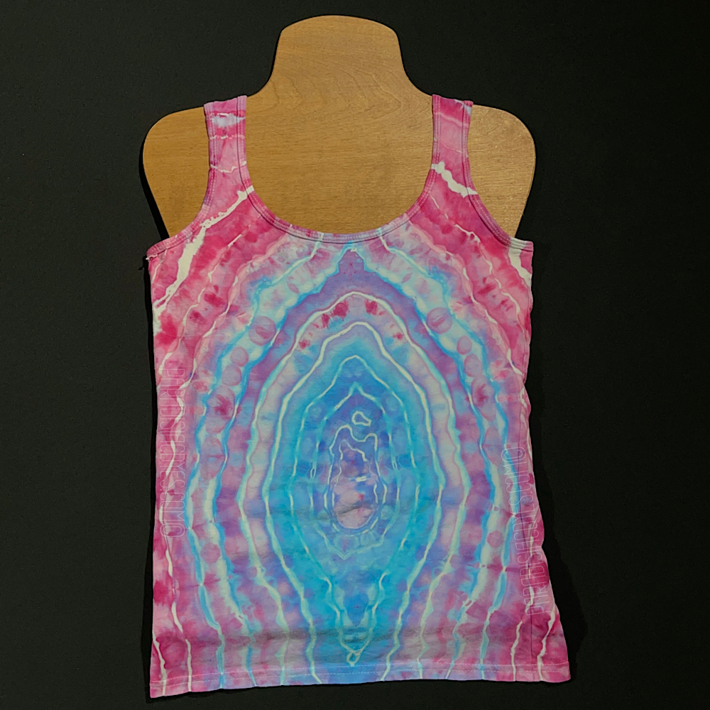 Front side of a ladies size small racerback style tank featuring a geode ice dyed design, with a giant, single geode on the front side with an ocean blue center, transitioning to pink as the bands expand outward