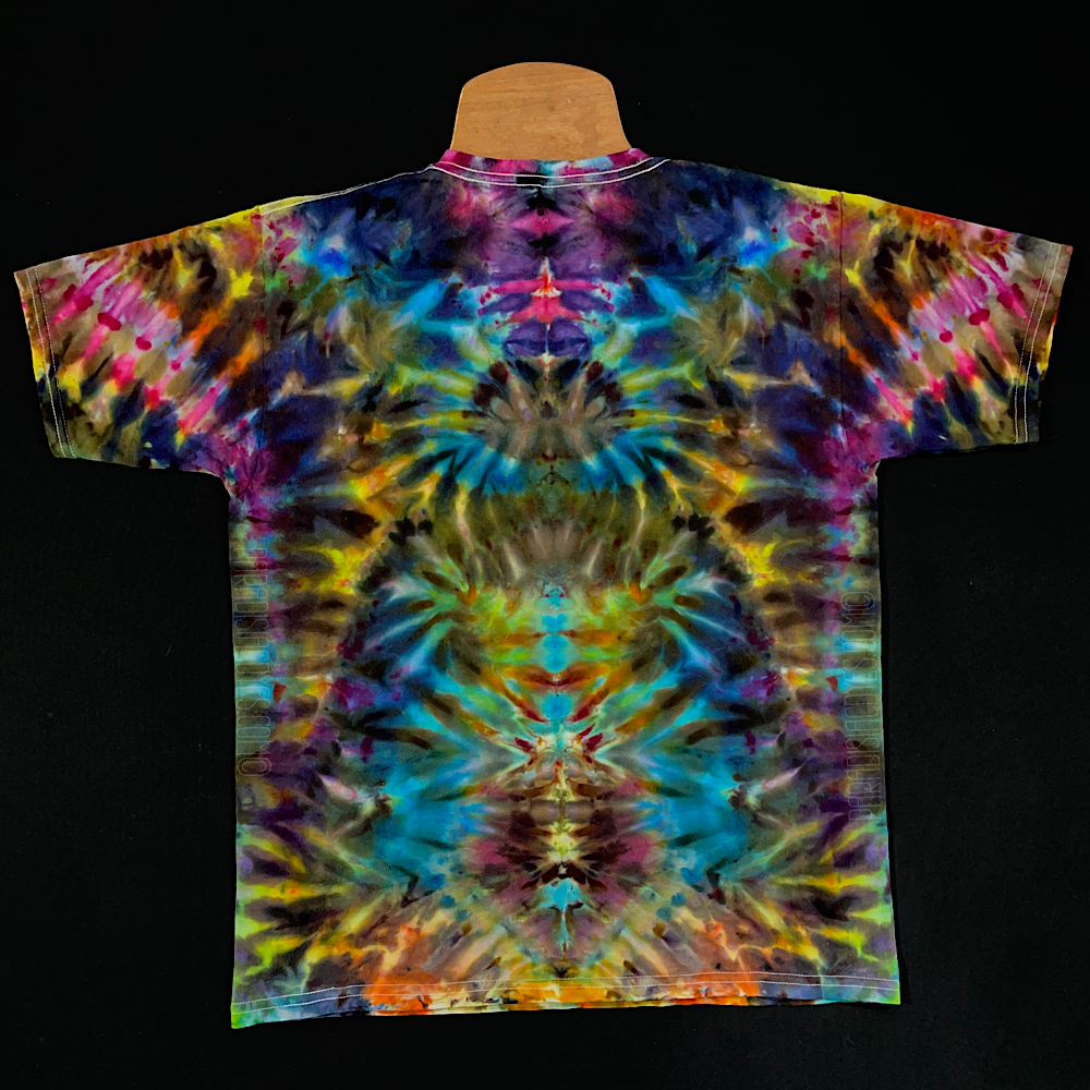 Front side of a children's tie dye shirt featuring vibrant rainbow colors throughout, in an abstract, symmetrical, totem pole-like pattern