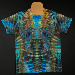 Front side of a short sleeve size adult medium tie dye shirt featuring an abstract, symmetrical, totem pole like ice dyed pattern in an array of blue, brown & golden shades 
