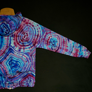 The back right arm sleeve of a size medium blue & pink agate geode tie dye zip hoodie, fully extended laid flat on a solid black background 