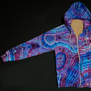 The front right sleeve of a size medium blue & pink geode ice tie dyed zip up hoodie; fully extended, laid flat on a solid black background 
